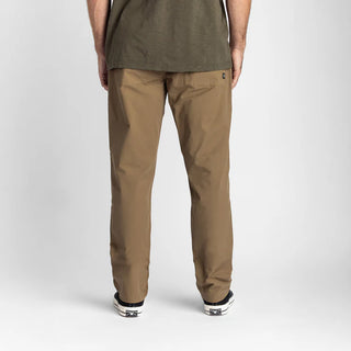 Roark Layover Pro Traveler Pants in Dark Khaki, straight-leg 4-way stretch Embarq Dura-Stretch fabric with TSA-friendly waistband, zippered travel pockets, back phone stash pocket, and laser-perforated cooling panel