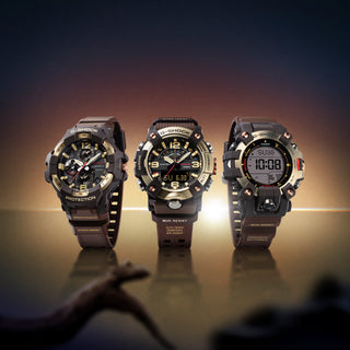 Front view of the G-SHOCK GGB100XMH-5A Mudmaster with a gold-tone bezel, dark brown case and band, black analog-digital dial, and red second hand
