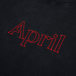 “Black April thermal long-sleeve shirt with red embroidered April lettering centered on the chest and ribbed cuffs.”