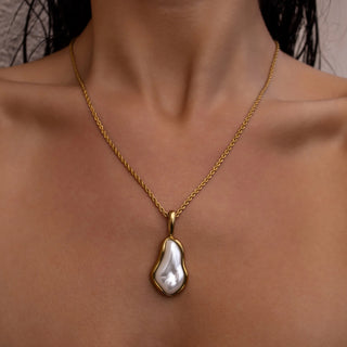 Gold necklace with glass pearl pendant and polished finish.