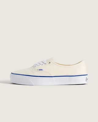 White Vans Authentic shoes with blue foxing stripe, white laces, and canvas uppers on a light neutral background.