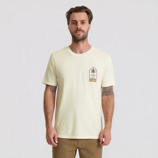 Man wearing a light-colored t-shirt with a small graphic on a plain background