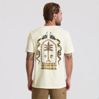 Man wearing a light-colored t-shirt with a palm tree design on the back, standing against a plain background.