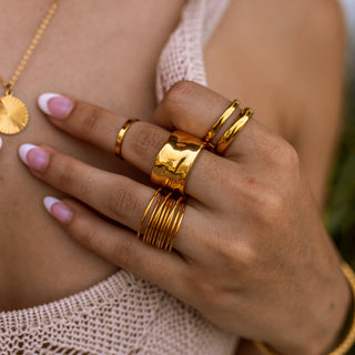 Gold sculptural ring with flowing ocean-inspired curves.