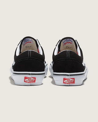 Black Vans sneakers with red and white labels on a beige background