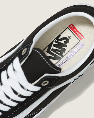 Black Vans sneaker with white laces on a light gray background