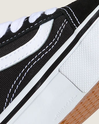 Close-up of a black and white sneaker with brown sole on a beige background