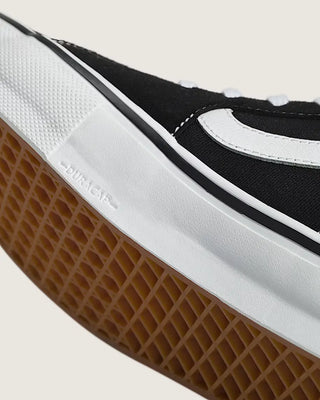 Close-up of a black and white sneaker with brown sole on a light gray background
