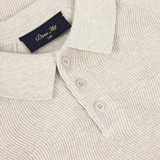 Close-up of a beige ribbed sweater with a brand label on a matching fabric background