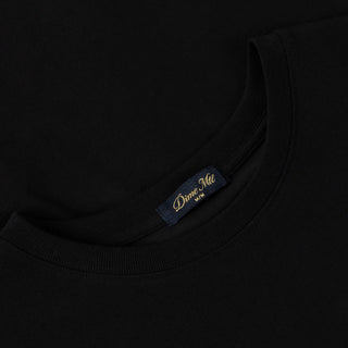 Close-up of a black garment with a brand label on a dark background