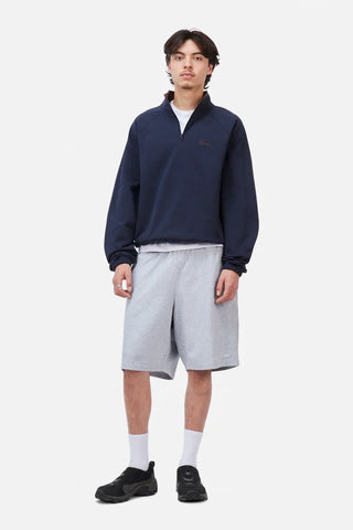 Person wearing a navy sweater and gray shorts on a white background