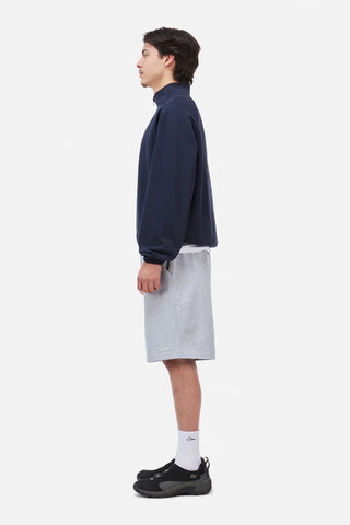 Person wearing a navy sweater and gray shorts on a white background
