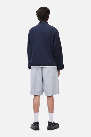 Person wearing a navy jacket and light gray shorts on a white background