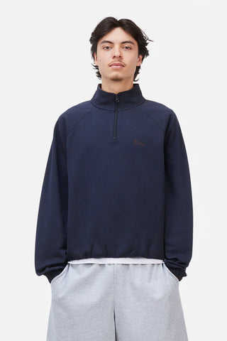 Person wearing a navy blue quarter-zip sweatshirt and gray pants on a light gray background