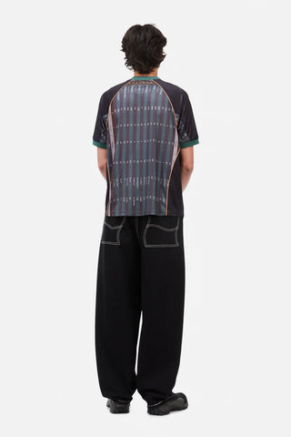 Person wearing a patterned shirt and black pants on a white background