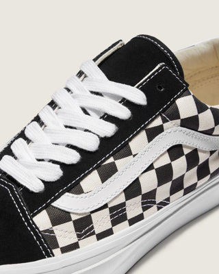 Black and white Vans Old Skool shoes with checkerboard canvas, suede overlays, white Sidestripe, and white rubber outsole.