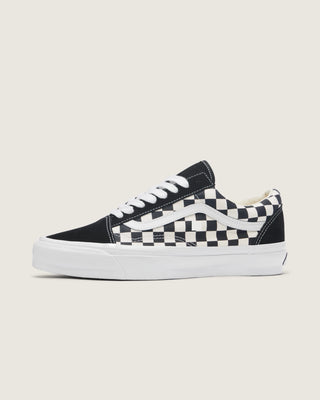 Black and white Vans Old Skool shoes with checkerboard canvas, suede overlays, white Sidestripe, and white rubber outsole.