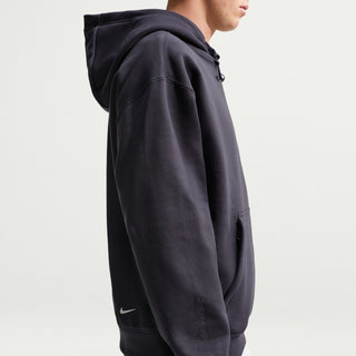 Side detail of the Nike ACG Tuff Fleece Pullover Hoodie in Gridiron/Summit White, showing the hood, sleeve embroidery, and white Swoosh at the rear hem.