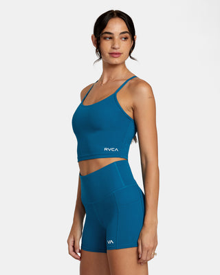 Active woman enjoying her workout in the RVCA VA Sport Base Tank Sports Bra, showcasing the scoop neck, racerback design, and the trendy half-moon cut-out at the back.