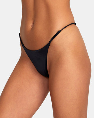 A confident woman wearing RVCA Solid Ultra Skimpy Bikini Bottoms, showcasing minimal coverage and a bold, fashionable look.