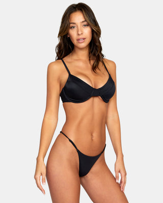 A confident woman wearing RVCA Solid Ultra Skimpy Bikini Bottoms, showcasing minimal coverage and a bold, fashionable look.