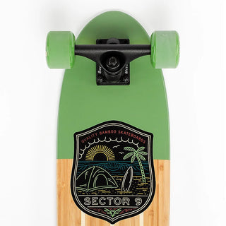 “Sector 9 Bambino Bivy complete skateboard with natural bamboo finish, green nose and wheels, black trucks, and beach camping badge artwork.”