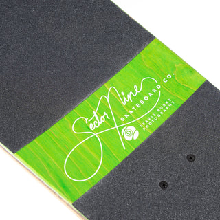 “Sector 9 Cascade Ninety Five complete skateboard showing mossy forest stream photography, woodgrain detailing, green-and-white wheels, and black grip tape.”