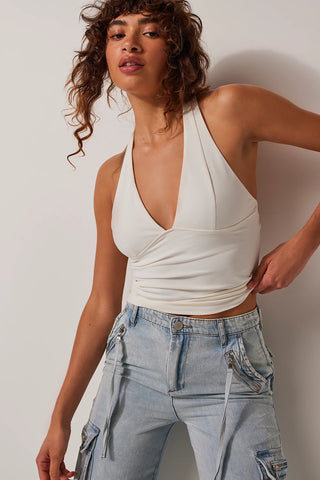Ivory halter top with plunging neckline and open back, slim fit.