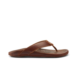 Side view of an OluKai Mekila sandal in Natural/Natural with brown leather straps, stitched edges, and decorative artwork across the footbed.