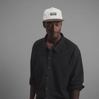melin Coronado Brick Hydro Hat in Frosted Birch with an off-white crown, brown flat visor, rectangular melin patch, patterned rope trim, and perforated side panels.
