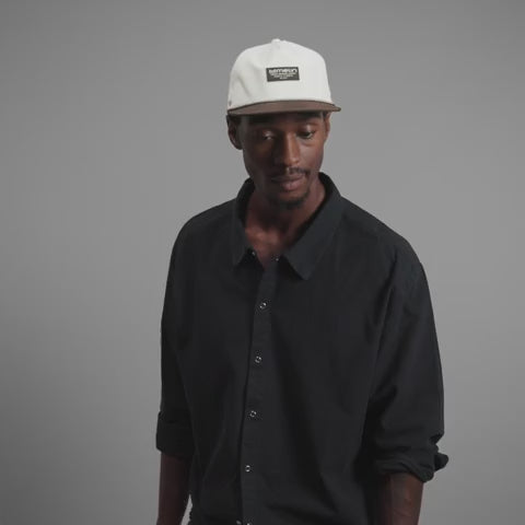 melin Coronado Brick Hydro Hat in Frosted Birch with an off-white crown, brown flat visor, rectangular melin patch, patterned rope trim, and perforated side panels.