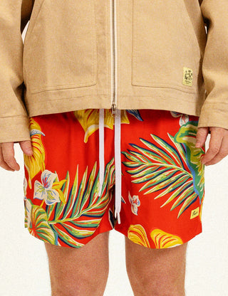 Model wearing Duvin Tropic Floral Swim Shorts in red with multicolored tropical flowers and leaves and a white drawstring