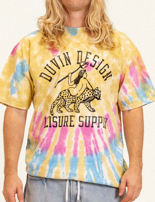 Model wearing the Duvin Leopard Tee in yellow, pink, and blue tie dye with a black leopard-and-rider graphic and Duvin Design Leisure Supply lettering
