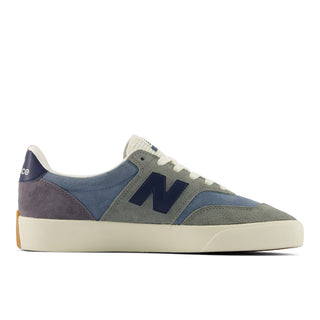 A New Balance sneaker in a muted colorway featuring dusty blue suede, gray suede, navy blue overlays, and an off-white rubber sole, shown from a side profile on a white background.