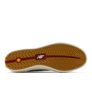 The outsole of a New Balance sneaker, showing a brown herringbone tread pattern with a burgundy stripe, a yellow Vibram logo, and a white midsole.