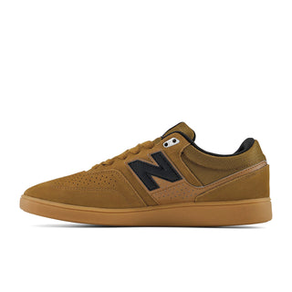 A New Balance low-top sneaker in a warm brown/tan colorway, featuring a prominent black 'N' logo on the side, black laces, and a matching brown gum sole, shown against a plain white background.
