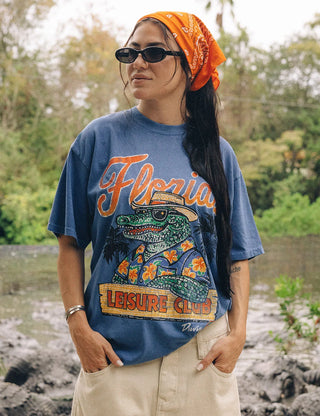 Duvin x Florida Gators Leisure Club Tee with orange Florida lettering and Albert wearing sunglasses and a Hawaiian shirt behind a Leisure Club sign.