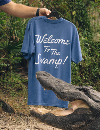Duvin x Florida Gators Leisure Club Tee with orange Florida lettering and Albert wearing sunglasses and a Hawaiian shirt behind a Leisure Club sign.