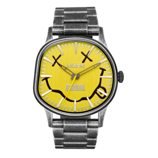 Nixon watch with yellow face and metal band on white background
